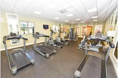 a gym with several treadmills and elliptical machines at Two-Bedroom Townhome Kissimmee in Orlando