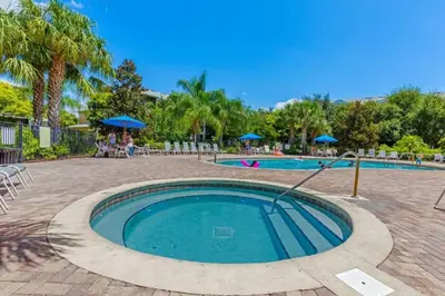 a swimming pool in a park with people sitting under umbrellas at Three-Bedroom Townhome Kissimmee in Orlando