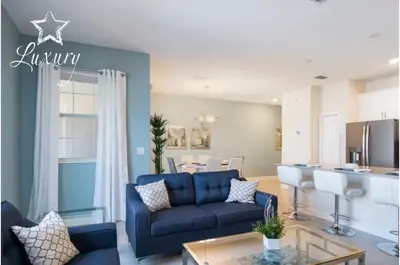 a living room with a blue couch and a kitchen at Four-Bedroom Townhome Kissimmee in Orlando