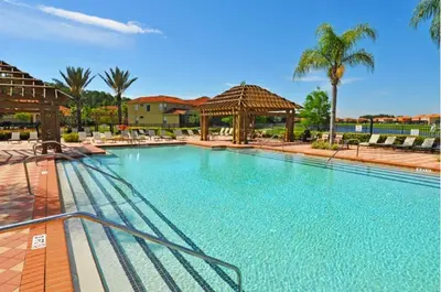 a large swimming pool with a gazebo and palm trees at Four-Bedroom Townhome Kissimmee in Orlando