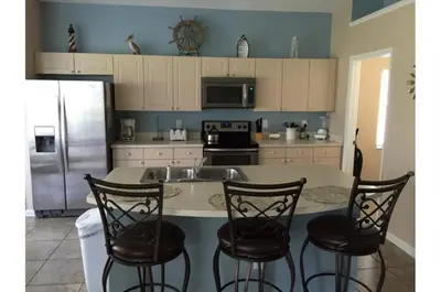 a kitchen with a counter with chairs and a refrigerator at Three-Bedroom Pool Home Kissimmee in Orlando