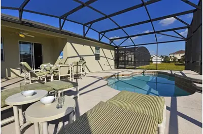 a patio with tables and chairs and a swimming pool at Three-Bedroom Pool Home Kissimmee in Orlando