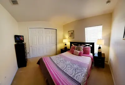 a bedroom with a bed with pink sheets and a door at Four-Bedroom Pool Home Kissimmee in Orlando