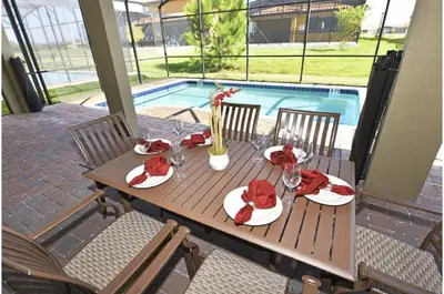 a wooden table with plates of food on a patio at Five-Bedroom Pool Home Kissimmee in Orlando