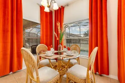 a dining room with orange curtains and a table and chairs at Five-Bedroom Pool Home Kissimmee in Orlando
