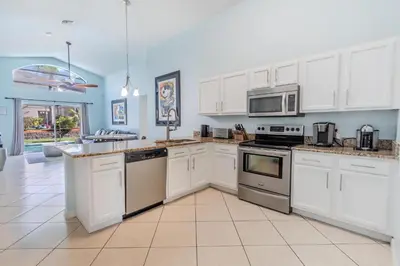 a kitchen with white cabinets and stainless steel appliances at 4-Bed Home Near Disney Private Pool in Kissimmee