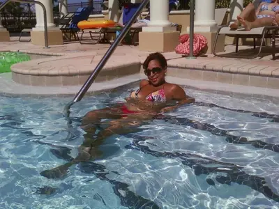 a woman is sitting in a swimming pool at DREAM Vacation BY A3G in Orlando