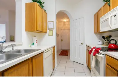 a kitchen with wooden cabinets and a sink at DREAM Vacation BY A3G in Orlando