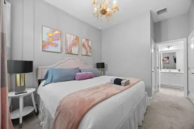 a bedroom with a large bed and a chandelier at 12BR Disney Home | Sleeps 30+, GameRoom, POOL/SPA! in Kissimmee