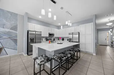 a kitchen with a large island with bar stools at 12BR Disney Home | Sleeps 30+, GameRoom, POOL/SPA! in Kissimmee