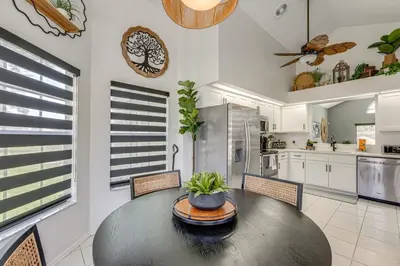 a kitchen with a table and chairs and a kitchen with white cabinets at Disney Getaway with Private Hot Tub 14 Mi to Parks in Kissimmee