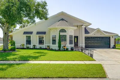 a white house with a driveway and grass at Disney Getaway with Private Hot Tub 14 Mi to Parks in Kissimmee