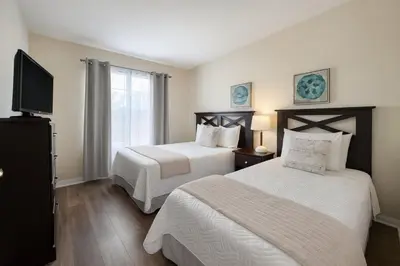a bedroom with two beds and a flat screen tv at Casa 5 Quartos Vista Lago – Perto da Disney! in Kissimmee