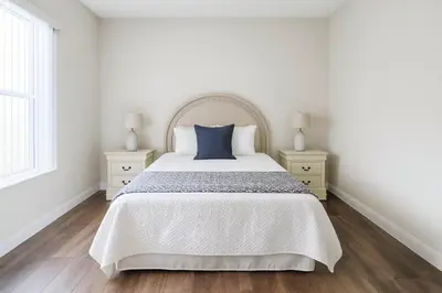 a white bedroom with a large bed and two night stands at Casa 5 Quartos Vista Lago – Perto da Disney! in Kissimmee