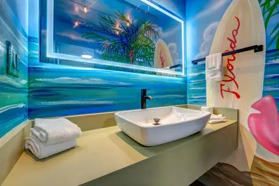 a bathroom with a sink and a surfboard mural at Surf and Sun Stitch Studio Kissimmee in Kissimmee