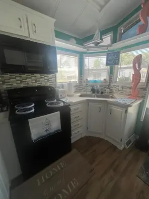a kitchen with white cabinets and a black stove top oven at Cozy Private Cottage Only 5 miles from Disney in Kissimmee