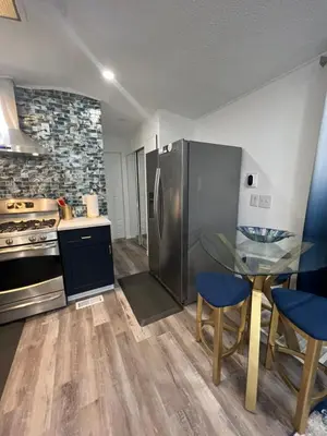 a kitchen with a table and a stainless steel refrigerator at Luxury Tiny Cottage 5 miles from Disney in Kissimmee