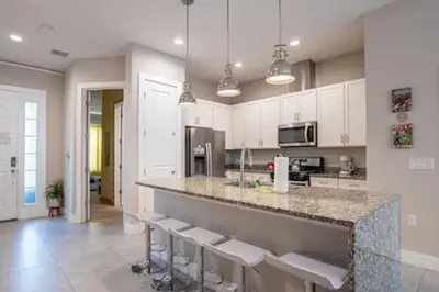 a kitchen with a counter with stools in it at 4 Luxurious Suites Near Theme Parks and Downtown in Orlando