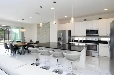 a kitchen with white cabinets and a black counter top at Luxuosa Villa 9 Suítes c/ Piscina Sonoma Resort in Kissimmee