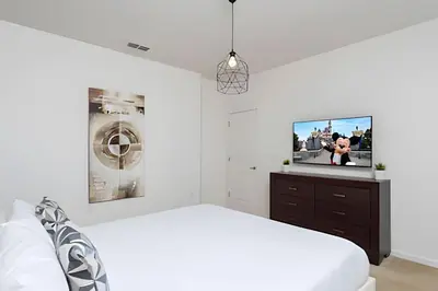 a white bedroom with a bed and a tv at Luxuosa Villa 9 Suítes c/ Piscina Sonoma Resort in Kissimmee