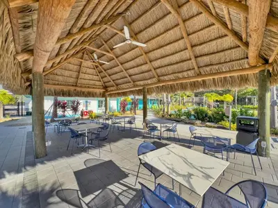 a patio with tables and chairs under a wooden roof at Casa Disney 5 Quartos c/ Piscina – 13 Pessoas in Kissimmee