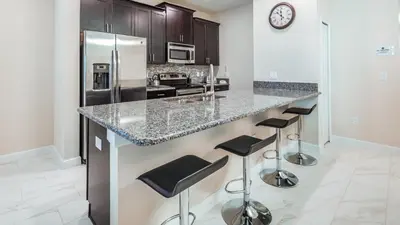 a kitchen with a stainless steel refrigerator and stools at GRH9244 - Storey Lake Resort - 5 Bed 4 Baths Townhome in Kissimmee