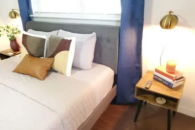 a bed with pillows and a side table with books at Bungalow DT by Lake Eola KIA center Sleeps 12 in Orlando