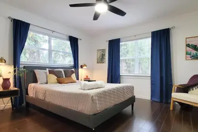 a bedroom with a bed with blue curtains and a ceiling fan at Bungalow DT by Lake Eola KIA center Sleeps 12 in Orlando