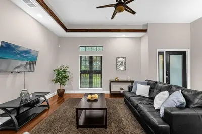 a living room with a black leather couch and a ceiling fan at Florida Summer - Townhome 5 min from Disney in Orlando