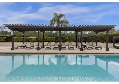 a pool with a pergola and chairs next to a swimming pool at Sunny Summer Deals - Renovated TownHome by Disney in Orlando