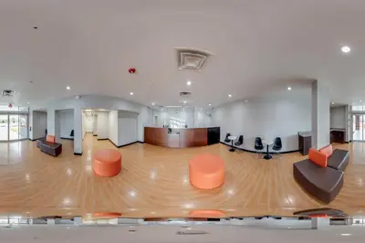 a large room with orange chairs and a wooden floor at Hotel O Orlando Airport near Florida Mall in Orlando