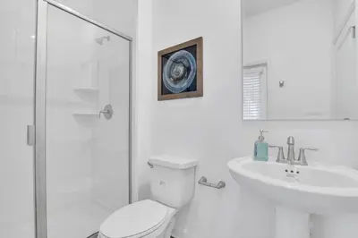 a white bathroom with a toilet and a sink at Stunning 7BR Resort Pool Home 13 Min Disney in Kissimmee