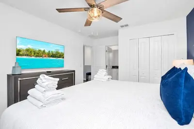 a white bedroom with a large bed with a flat screen tv at Stunning 7BR Resort Pool Home 13 Min Disney in Kissimmee