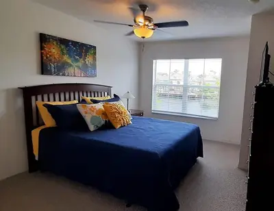 a bedroom with a blue bed with a ceiling fan at Beautiful Townhome In a Resort Near Disney in Kissimmee