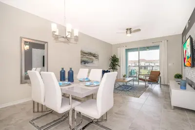 a dining room with a table and white chairs at Disney Getaway Luxury Condo with Private Balcony. Book Now SLR366 in Kissimmee