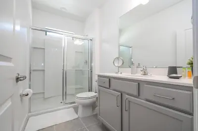 a white bathroom with a toilet and a shower at Disney Private Pool Game Room Themed Bedrooms. Book Now PG20 in Orlando