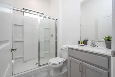 a white bathroom with a toilet and a shower at Disney Private Pool Game Room Themed Bedrooms. Book Now PG20 in Orlando