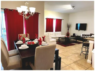 a living room with a dining table and red curtains at Disney Getaway Townhouse with Private Pool. Book Now SLR484 in Kissimmee