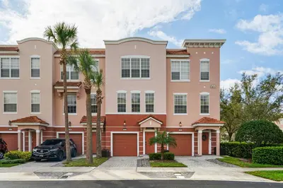 a large pink building with palm trees in a parking lot at Disney Getaway Townhouse with Private Pool. Book Now VC304 in Orlando