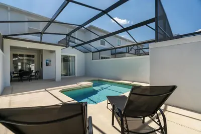 a house with a swimming pool and two chairs at Disney Getaway Private Pool Themed Bedrooms. Book Now SLR481 in Kissimmee
