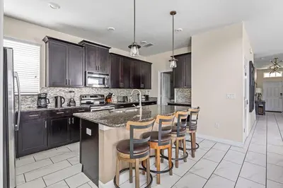 a kitchen with black cabinets and bar stools at Disney Private Pool Hot Tub Game Room Themed Bedrooms. Book Now SLR497 in Kissimmee