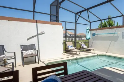 a swimming pool with two chairs and a table at Disney Getaway Private Pool Themed Bedrooms. Book Now SLR503 in Kissimmee