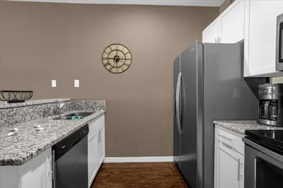a kitchen with a refrigerator and a clock on the wall at Disney Getaway Townhouse with Private Pool. Book Now WLV82 in Kissimmee