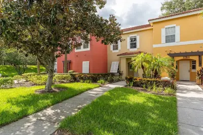 a house with a tree in the yard at Disney Getaway Townhouse with Private Pool. Book Now EIR68 in Kissimmee