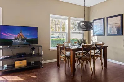 a dining room with a table with chairs and a tv at Disney Getaway Private Pool Themed Bedrooms. Book Now LV7 in Kissimmee
