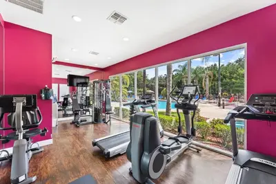a gym with a pink wall and tread machines at Disney Getaway Private Pool Themed Bedrooms. Book Now LV7 in Kissimmee