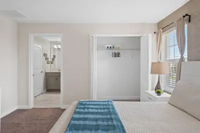 a white bedroom with a bed and a bathroom at Disney Getaway Townhouse with Private Pool. Book Now SLR504 in Kissimmee