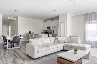 a living room with a white couch and a kitchen at Disney Getaway Villa with Private Pool Hot Tub. Book Now SLR502 in Kissimmee