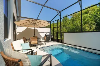 a swimming pool with chairs and an umbrella on a patio at Disney Getaway Private Pool Themed Bedrooms. Book Now PG54 in Orlando