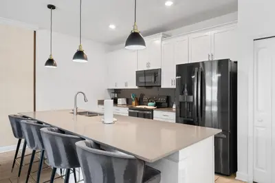 a kitchen with white cabinets and a stainless steel refrigerator at Disney Getaway Private Pool Themed Bedrooms. Book Now SLR370 in Kissimmee